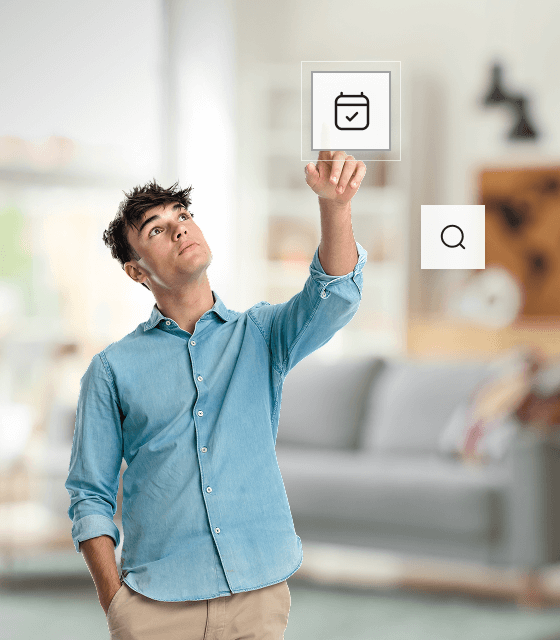A man in a blue shirt and slacks is pointing to an icon representing a calendar that is floating in mid air.